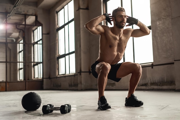 Uomo muscoloso che fa squat in palestra