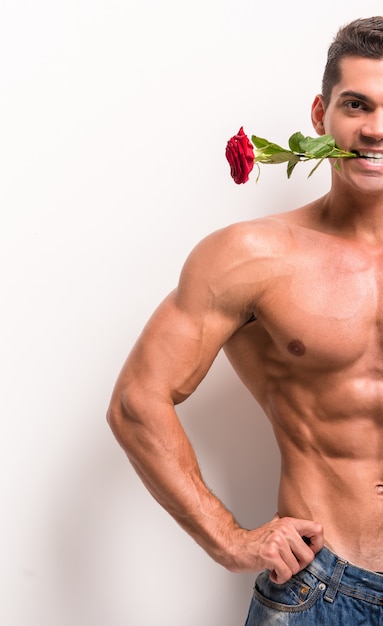 Uomo muscoloso con torso perfetto tiene in mano una rosa.