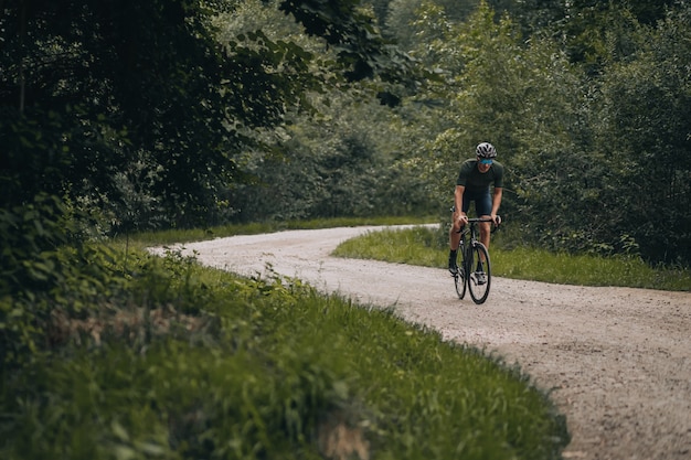 Uomo muscoloso in abiti sportivi in sella alla bici sul sentiero