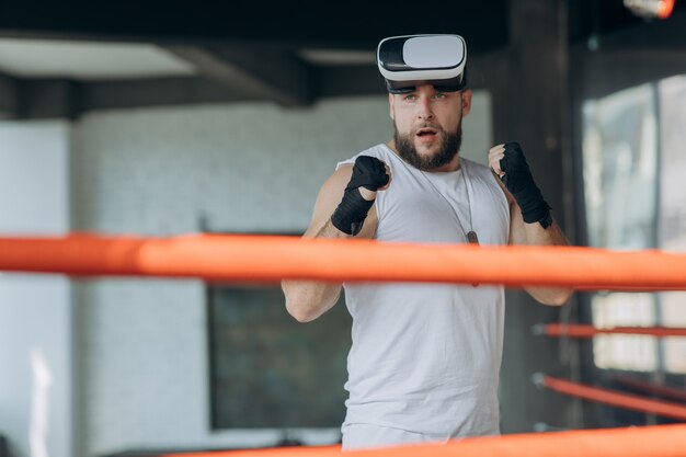 Uomo muscoloso in occhiali VR e guantoni da boxe