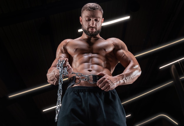 Uomo muscoloso in posa in palestra con una cintura atletica. Concetto di fitness.