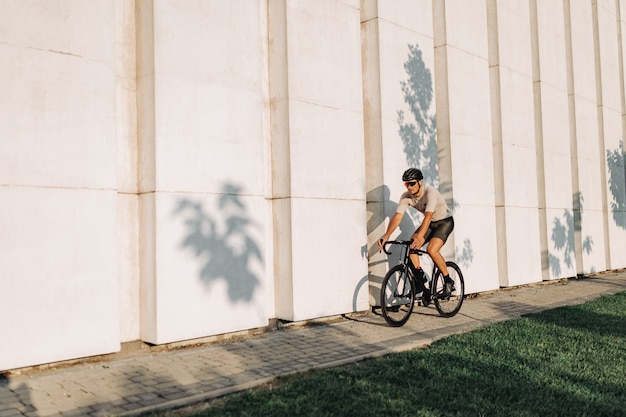 Uomo muscoloso in sella a una bici nera sulla strada della città