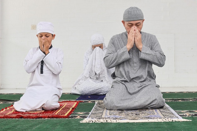 Uomo musulmano asiatico che diventa imam e conduce la sua famiglia a pregare Concetto di religione