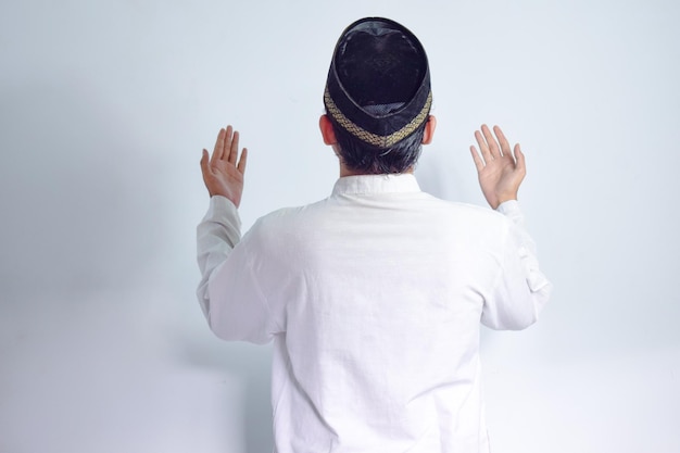 Uomo musulmano asiatico che indossa occhiali e stoffa bianca che prega a lato posteriore per il Ramadan e l'Eid al-Fitr