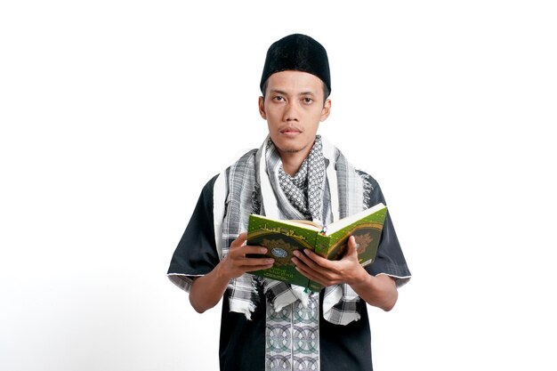 Uomo musulmano asiatico che indossa un abito musulmano turbante e un berretto che legge il Corano isolato su sfondo bianco