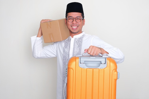 Uomo musulmano asiatico sorride eccitato mentre porta bagagli e scatole durante l'Eid Al-Fitr