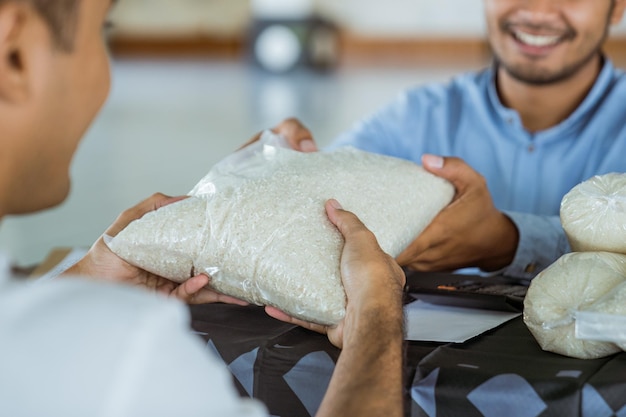 Uomo musulmano che dà un riso come donazione di cibo per la zakat durante l'eid mubarak