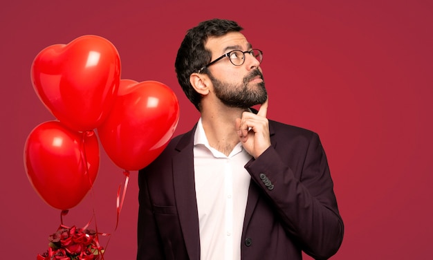 Uomo nel giorno di San Valentino che pensa un&#39;idea mentre osserva in su sopra priorità bassa rossa