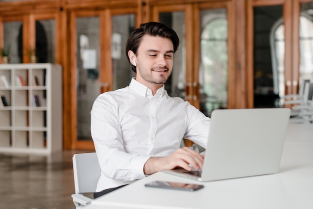 Uomo nel suo luogo di lavoro con il telefono e il computer portatile in ufficio