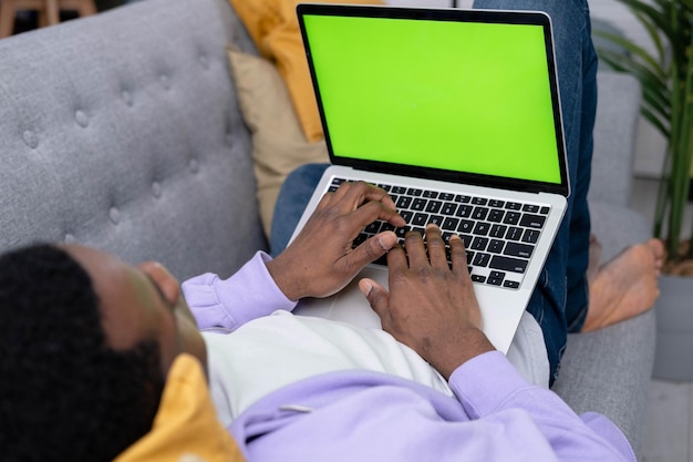 Uomo nero che utilizza laptop notebook visualizzazione schermo verde premere tastiera navigazione chiave cromatica African American freelancer online digitando testo lavorando in remoto sul computer vicino da casa