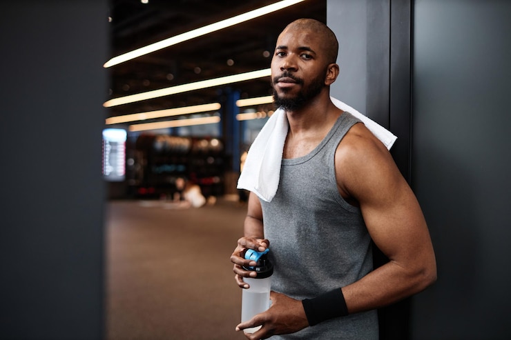 Foto uomo nero muscoloso che guarda la telecamera in palestra.