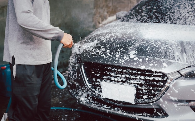 Uomo non identificato che lava un'auto con schiuma ad alta pressione