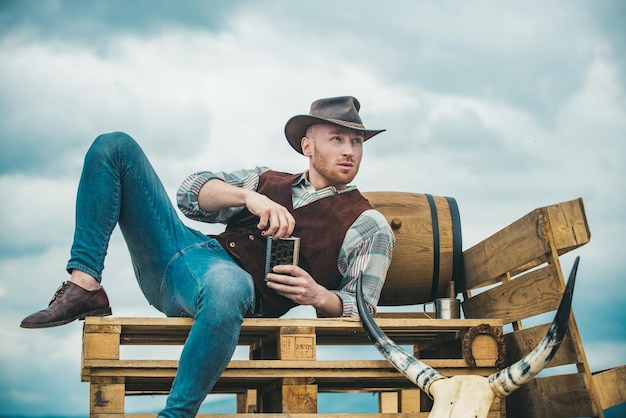 Uomo occidentale sexy con cappello da cowboy uomo attraente con whisky o brandy