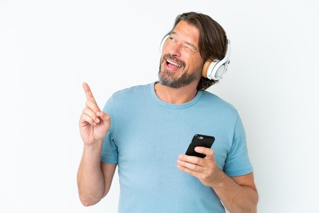 Uomo olandese anziano isolato su sfondo bianco ascoltando musica con un cellulare e cantando