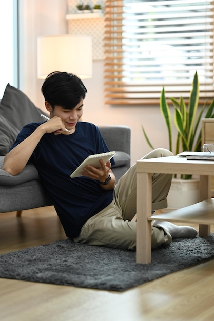 Uomo pacifico in abiti casual che legge la letteratura preferita in un accogliente soggiorno