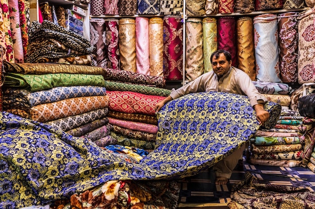 Uomo pakistano che vende tessuto colorato al Qissa Khwani Bazaar a Peshawar, Pakistan