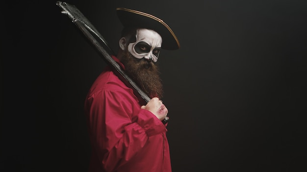 Uomo pazzo con trucco vestito come un pirata con un'ascia per la festa di halloween.