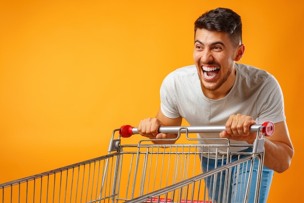 Uomo pazzo divertente che si precipita con il carrello della spesa in vendita