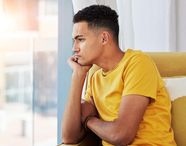 Uomo pensante e divano di casa con depressione e problemi nel soggiorno che si sentono annoiati e frustrati Triste dolore e salute mentale di una persona di sesso maschile sul divano con ansia e stanco per lo stress del fallimento