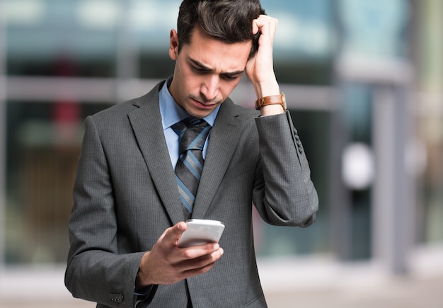 Uomo perplesso guardando il suo telefono