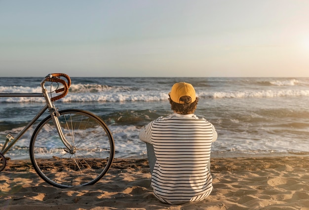 Uomo pieno del colpo che si siede sulla spiaggia