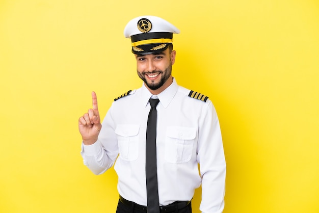 Uomo pilota arabo aereo isolato su sfondo giallo che mostra e solleva un dito in segno del meglio