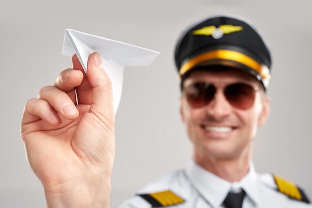 Uomo pilota sorridente che tiene un aeroplano di carta