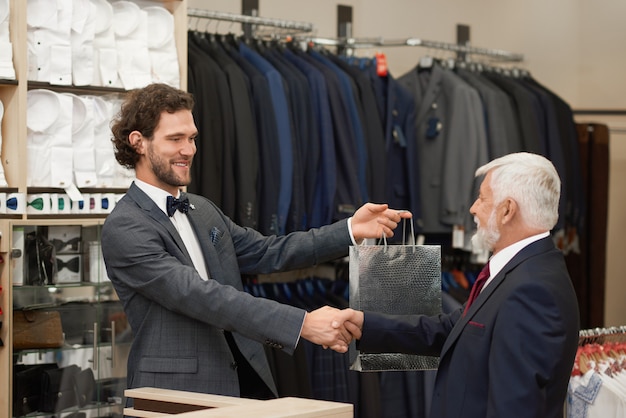 Uomo più anziano che dà la mano a sorridere al commesso.