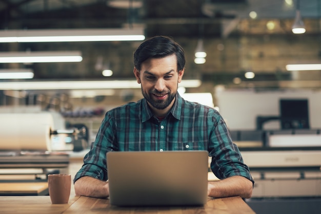 Uomo positivo con un laptop che sembra entusiasta mentre ci lavora sopra