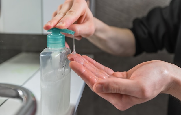 uomo premendo il distributore con sapone battericida