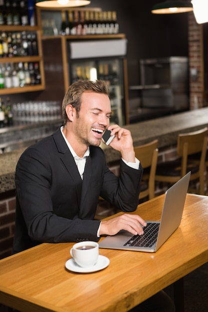 Uomo premuroso che per mezzo del computer portatile e dello smartphone