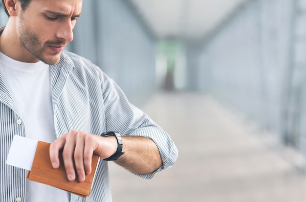 Uomo preoccupato che guarda l'orologio in attesa di imbarco in aeroporto