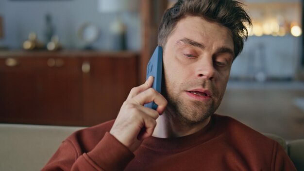 Uomo preoccupato che parla con lo smartphone nell'appartamento ritratto da vicino ragazzo serio chiamata
