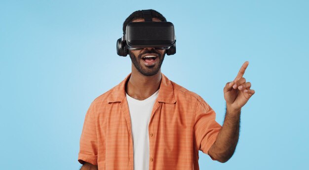 Uomo realtà virtuale e occhiali in studio con la mano clicca e scorri con il sorriso per metaverse su sfondo blu Persona AR visione e gioco futuristico con esperienza utente 3D cyber ui ed esports