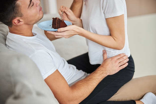 Uomo rilassato che mangia torta al cioccolato con la sua ragazza