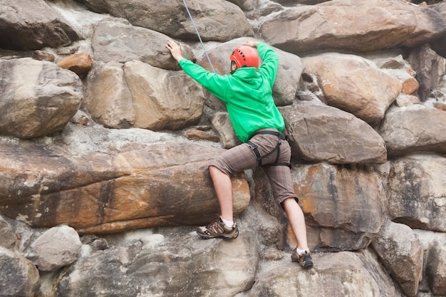 Uomo risoluto che scala un&#39;enorme parete rocciosa