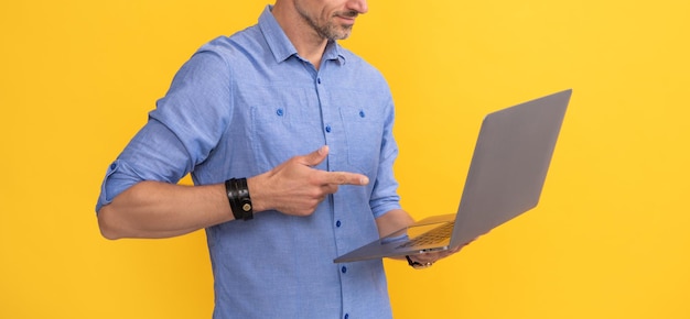 Uomo ritagliato che punta il dito sul computer su sfondo giallo, business online.