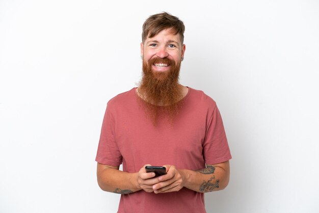 Uomo rosso con barba lunga isolato su sfondo bianco che invia un messaggio con il cellulare