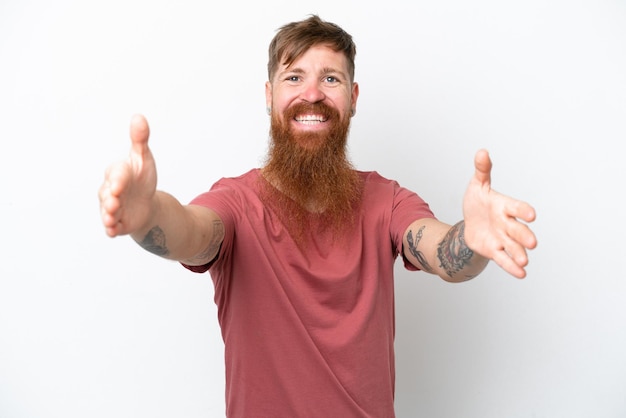 Uomo rosso con barba lunga isolato su sfondo bianco che presenta e invita a venire con la mano