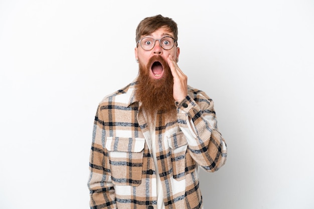 Uomo rosso con barba lunga isolato su sfondo bianco con espressione facciale sorpresa e scioccata