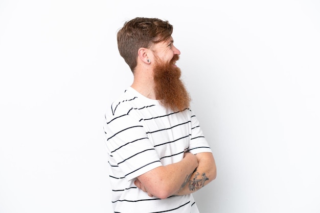 Uomo rosso con la barba isolato su sfondo bianco che guarda di lato e sorridente