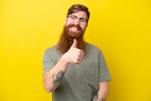 Uomo rosso con la barba isolato su sfondo giallo che dà un pollice in alto gesto