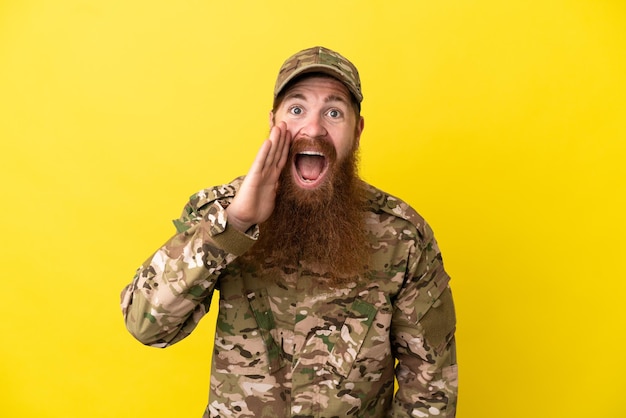 Uomo rosso militare sopra isolato su sfondo giallo che grida con la bocca spalancata