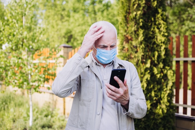 Uomo scioccato con mascherina medica usando il telefono per cercare notizie