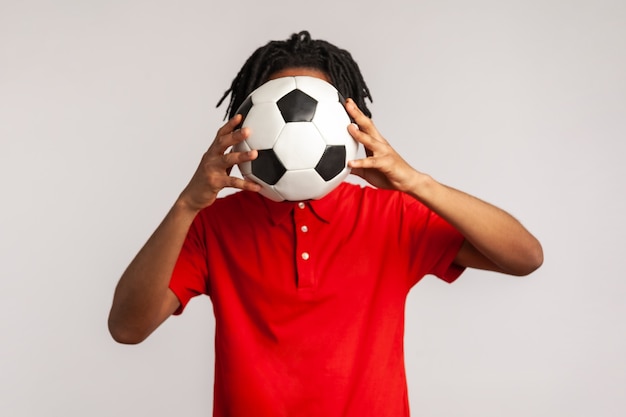 Uomo sconosciuto che si nasconde dietro un pallone da calcio, tifoso che si copre la faccia durante la partita.