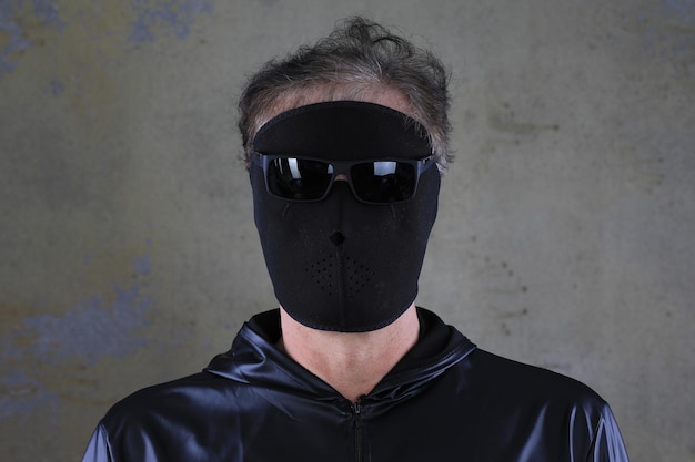 uomo sconosciuto con una maschera nera su uno sfondo nero