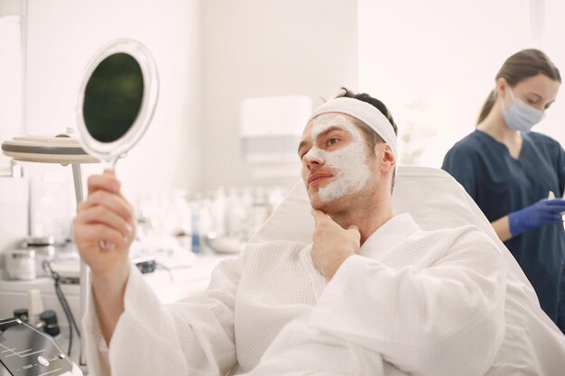 Uomo sdraiato nel gabinetto del cosmetologo con una maschera applicata sul viso