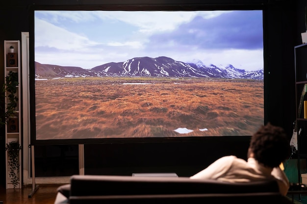 Uomo sdraiato sul divano che guarda un documentario di viaggio con una bellissima cinematografia