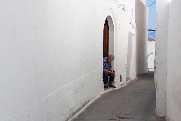 Uomo seduto all'ingresso della sua casa a Lindos Rodi Grecia
