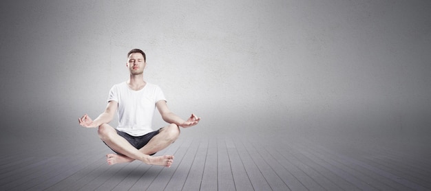 Uomo seduto in posizione loto yoga con gli occhi chiusi in palestra Concetto di rilassamento e meditazione con luogo mockup